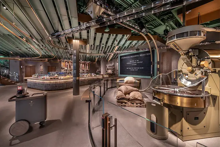 The large roaster on the ground floor of the Chicago Roastery, with bags of coffee beans nearby, and a network of tubes transporting coffee beans to and from the roaster
