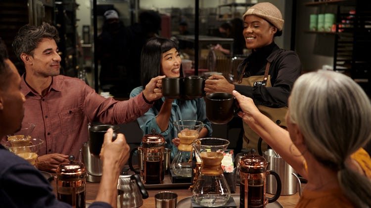 People raising their coffee cups to cheers.